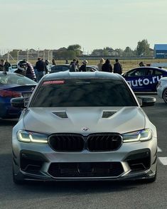 several cars are parked in a parking lot with people standing around and looking at them