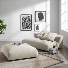 a living room with white furniture and pictures on the wall, including a footstool