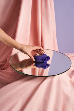 a person is cleaning a glass table with blue cloths on it and a pink curtain in the background