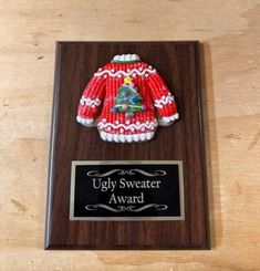 an ugly sweater award is displayed on a wooden plaque