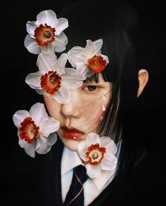 a woman with flowers in her hair and suit on, behind her is an image of white daffodils