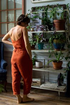 a woman in an orange jumpsuit looking at plants