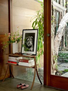 a small table with books and pictures on it in front of a door that leads to a patio