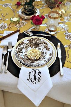 the table is set with gold and white plates, silverware, and napkins