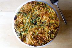 an overhead view of a quiche on a plate with a fork and spoon next to it