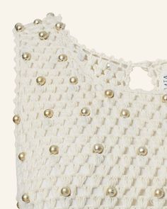 a white crochet bag with gold buttons on it