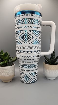 a white and blue coffee cup next to some succulents