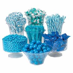 a bowl filled with blue and white candies next to two vases full of candy