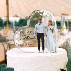 a clear heart shaped cake topper with a couple holding hands