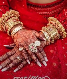 a woman's hands with henches and bracelets on her arm, wearing red dress