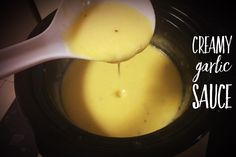 creamy garlic sauce in a crock pot with a spoon