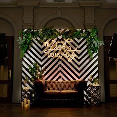 a couch sitting on top of a hard wood floor next to a wall covered in greenery