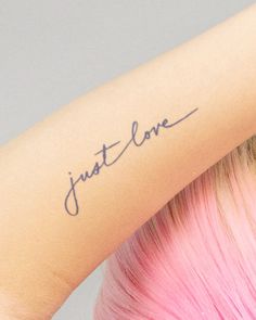 a woman with pink hair has a tattoo on her arm that says just love in cursive writing