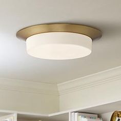 a ceiling light in a kitchen with white cabinets and gold trim on the wall behind it