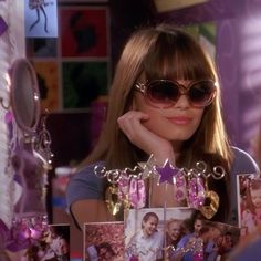 a woman wearing sunglasses sitting in front of a table with pictures and jewelry on it