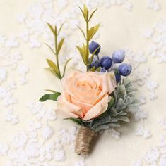 a boutonniere with flowers and leaves on a white lace tablecloth background