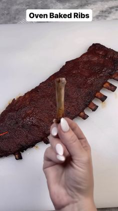 a person holding a stick in front of a large piece of meat