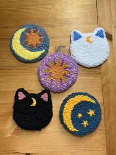 four crocheted coasters with cats and moon designs on them sitting on a wooden surface