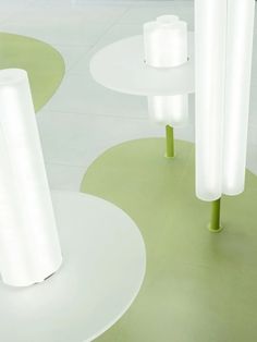 three white tables with green bases and lights in the middle one has a round table on it