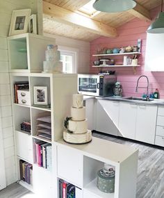 there is a cake sitting on top of the bookcases in this small kitchen