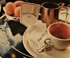 a cup of coffee sitting on top of a white saucer next to some eggs