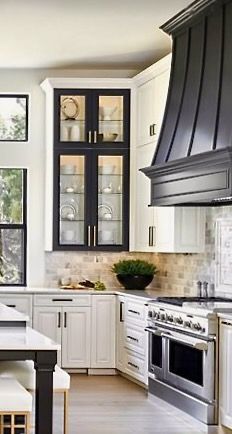 a large kitchen with white cabinets and black stove top ovens in front of a window