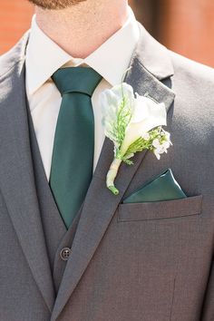 a man wearing a suit and tie with a boutonniere on his lapel