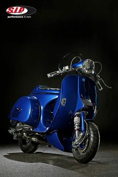 a blue motor scooter parked on top of a cement floor next to a black background