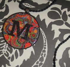 a necklace with the letter m on it is sitting on a black and white background