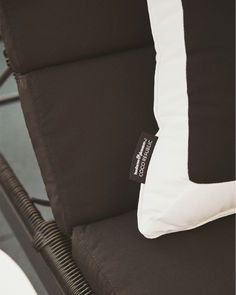 Close-up of a black cushion with white piping on a lounge chair, showcasing the luxurious Coco Republic x Business & Pleasure Co. collaboration tag, embodying both elegance and comfort. Cooler Tote Bag