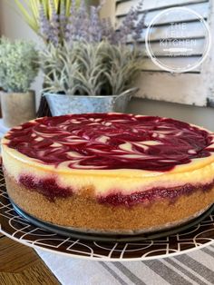 a cheesecake covered in red and white toppings on a wire rack next to potted plants