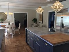 a large kitchen with an island in the middle and two chandeliers hanging from the ceiling