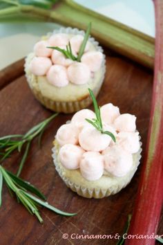 two small cupcakes with marshmallow toppings on a wooden tray