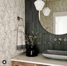 a bathroom with a sink and mirror next to a wallpapered wall behind it