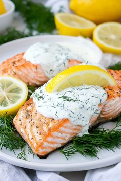 two salmon fillets on a plate with lemons and dill