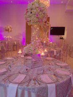 a table set up for a formal function with flowers and candles in the centerpieces