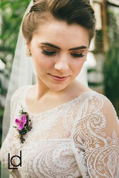 a woman in a wedding dress with a veil on her head and flowers in her hair