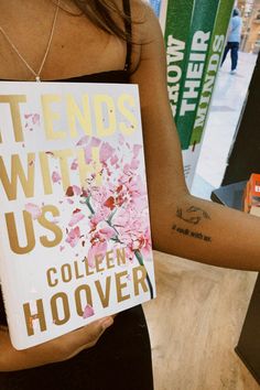 a woman holding up a book with flowers on it