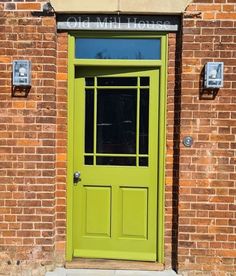 a bright green door on the side of a brick building