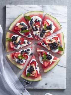 slices of watermelon and berries arranged on a marble platter with utensils