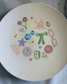 a white plate with different colored drawings on the front and back of it's surface