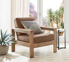 a brown chair sitting in front of a window next to a potted plant