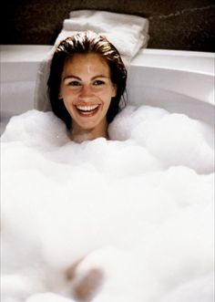 a woman smiles as she takes a bubble bath