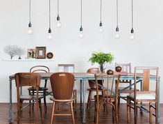 a dining room table with chairs and lights hanging from the ceiling