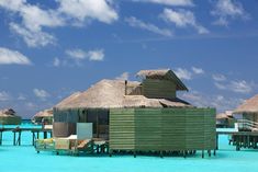 an over water resort with thatched huts and lounge chairs