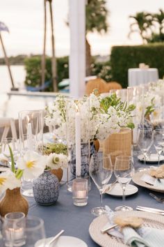 the table is set with white flowers and silverware