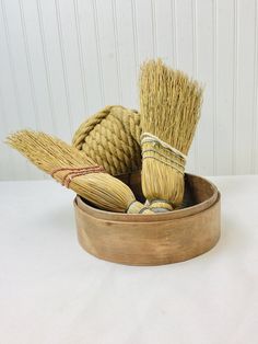 two brooms in a wooden bowl on a white table