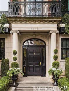 a black door surrounded by potted plants in front of a house