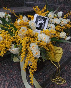 a bouquet of yellow and white flowers with a photo pinned to the back of it