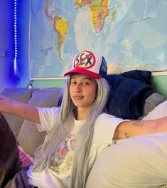 a woman with long grey hair wearing a red and white hat sitting on a couch